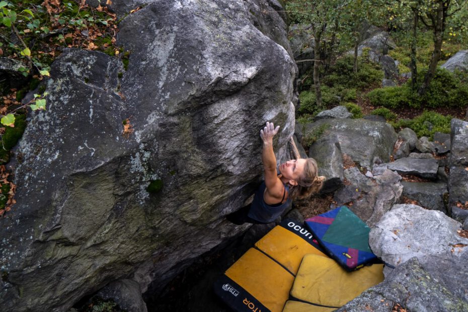 Frau bouldern mit Boulderausrüstung am Felsen